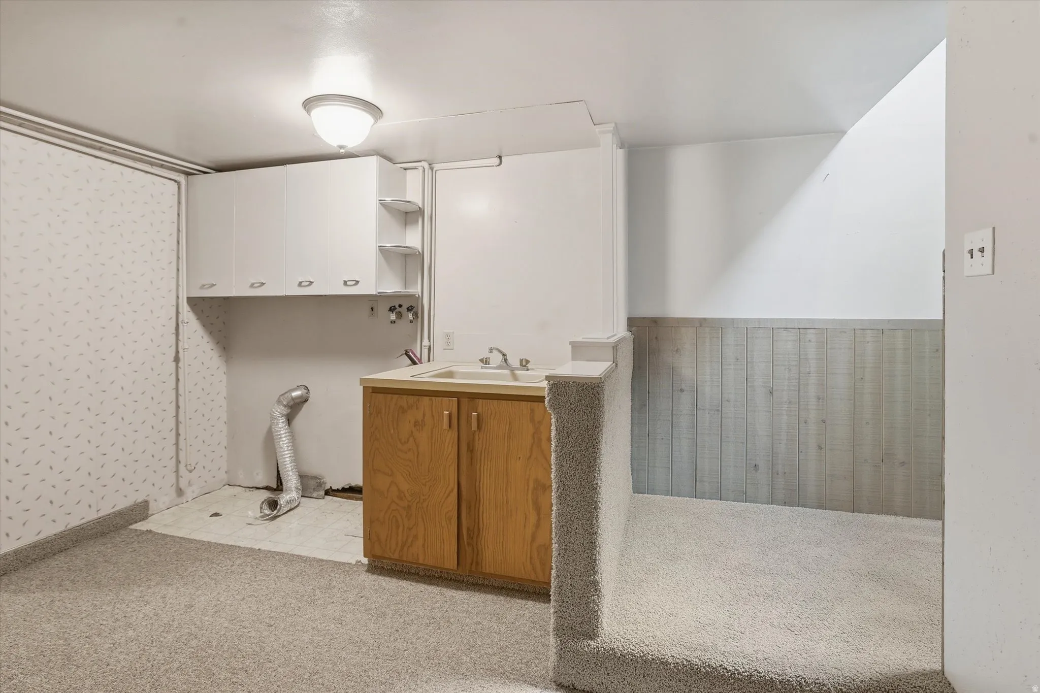 Utility area featuring a built-in sink with wood-finish cabinetry, overhead white cabinetry, and open shelving