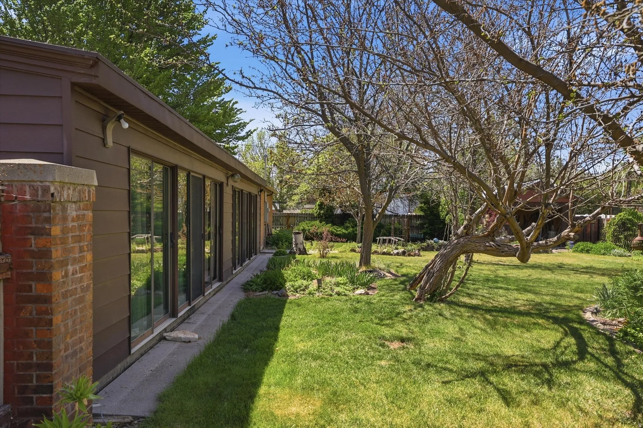 Expansive rear yard featuring a manicured lawn, established landscaping, and mature trees