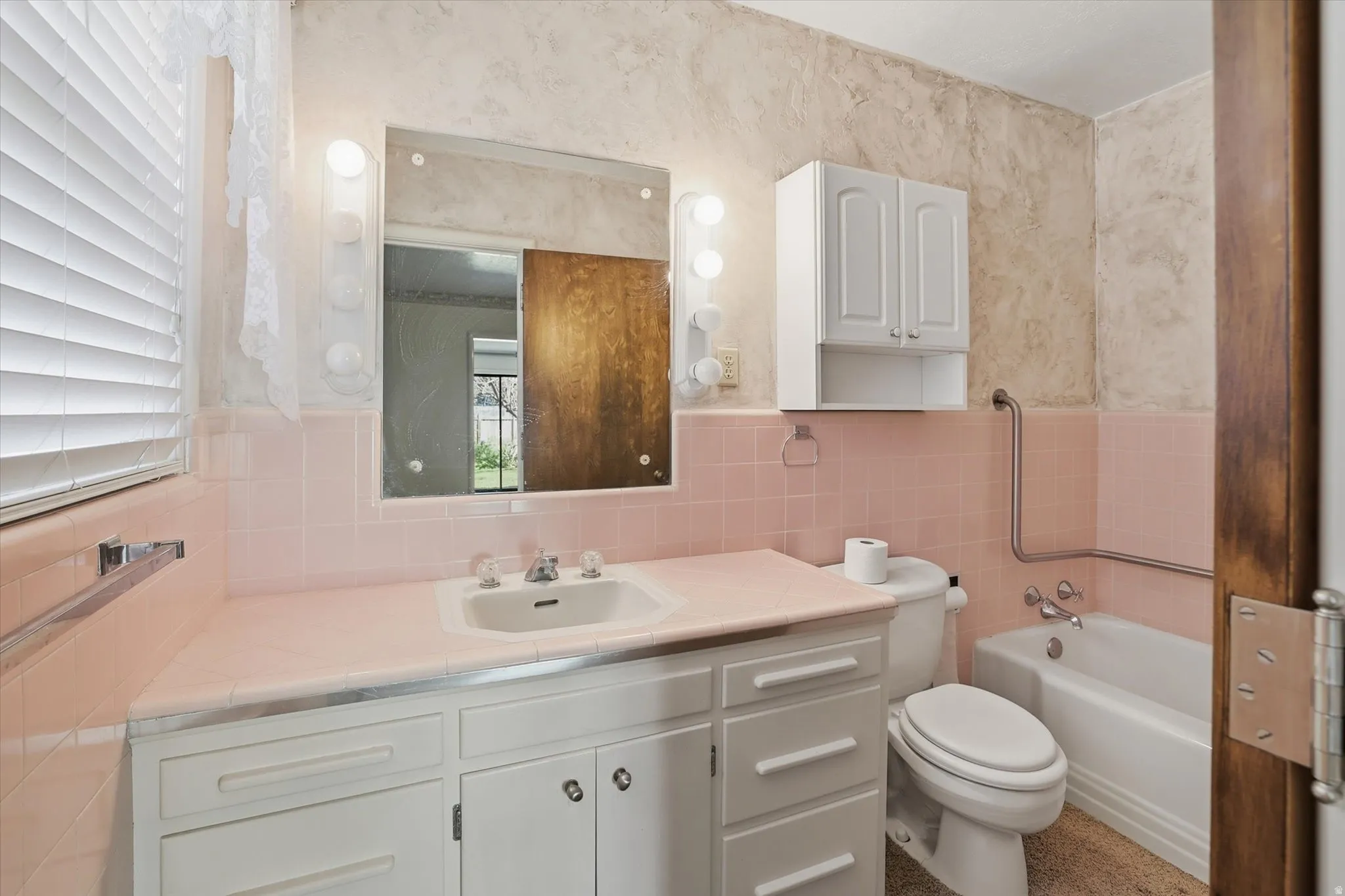 Bathroom featuring a white vanity with integrated sink, a built-in bathtub, and a wall-mounted medicine cabinet