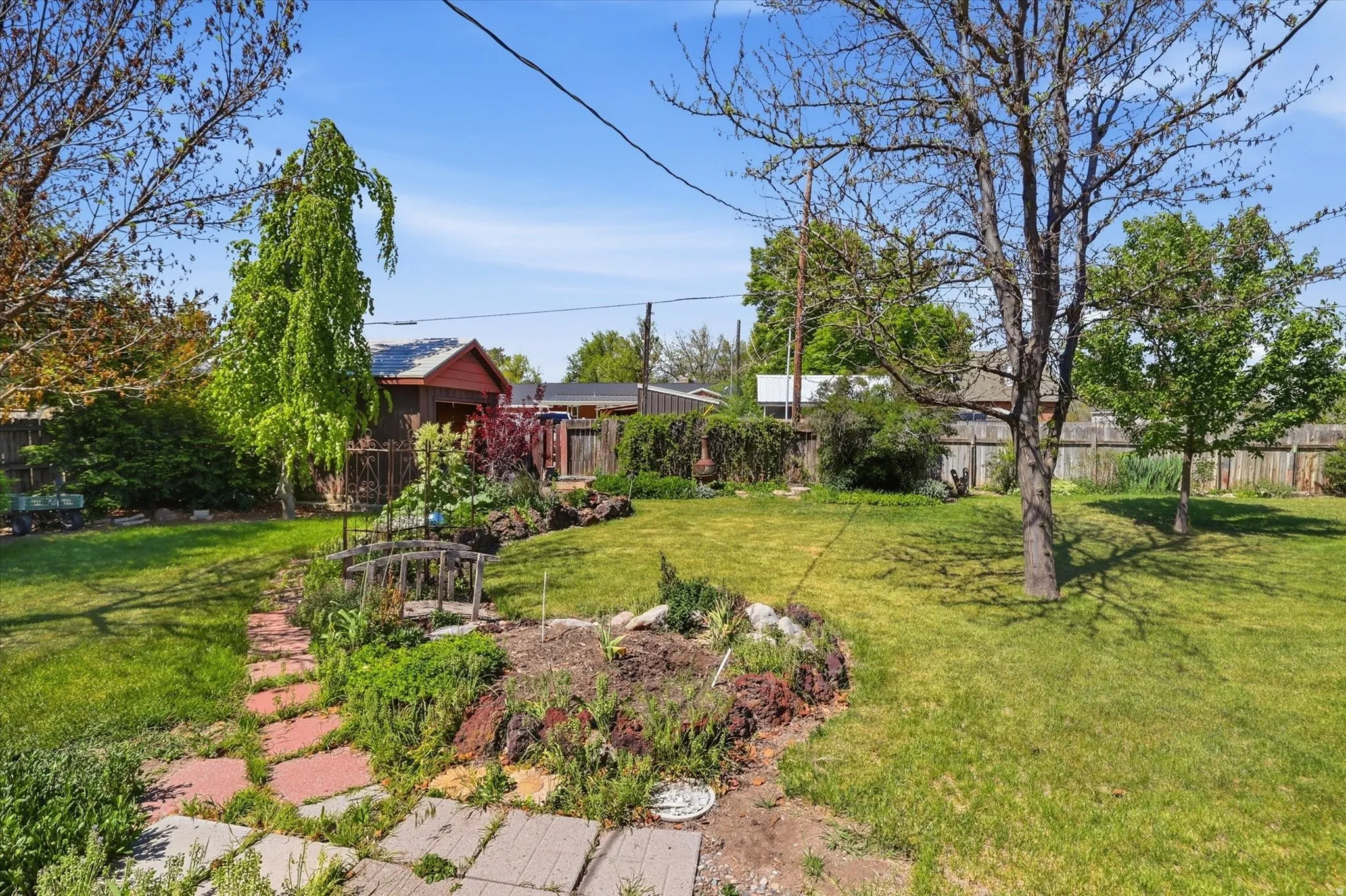 Expansive yard featuring a manicured lawn, established trees, and mature landscaping