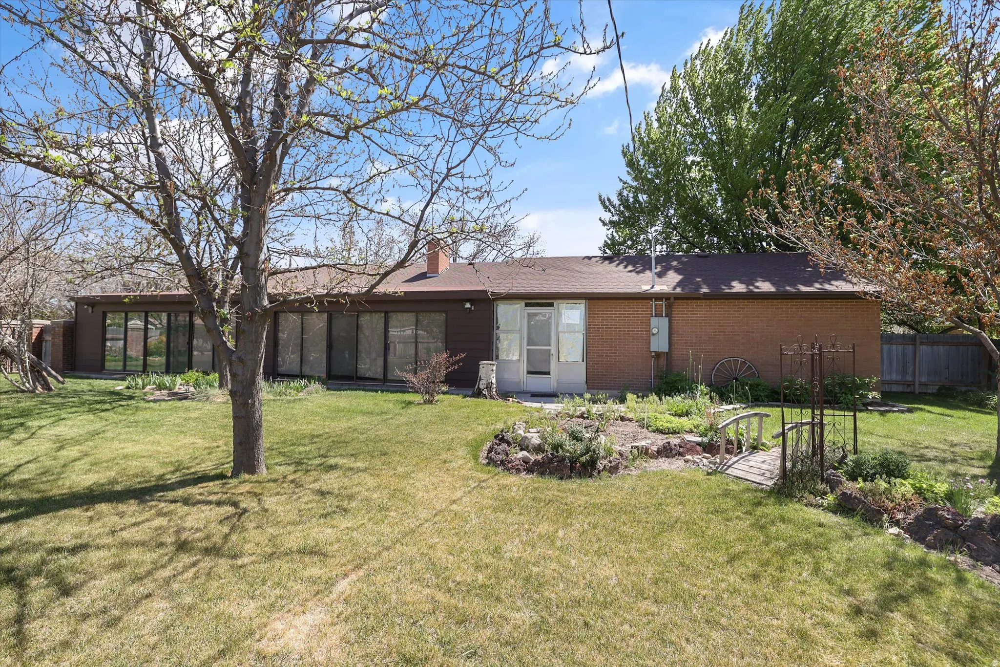 Expansive backyard featuring a manicured lawn, established trees, and a terraced garden area