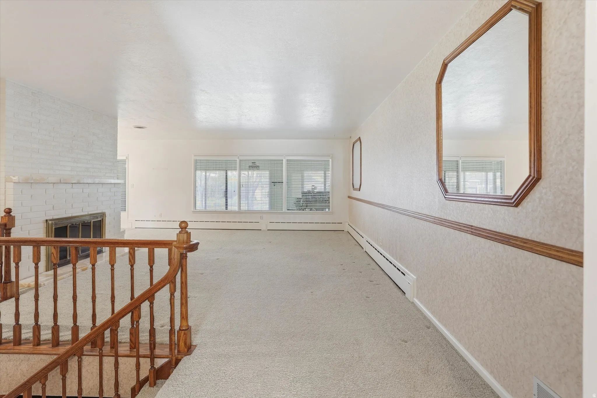 Room featuring a white brick fireplace, sliding glass door, and a wooden banister