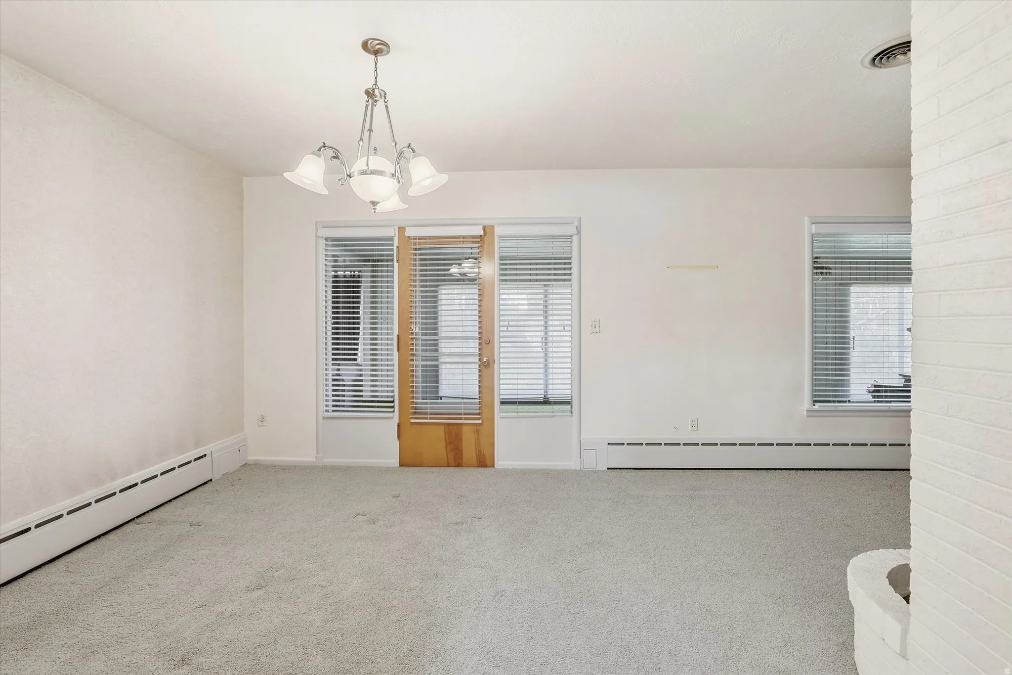 Carpeted interior space featuring white walls and a central chandelier