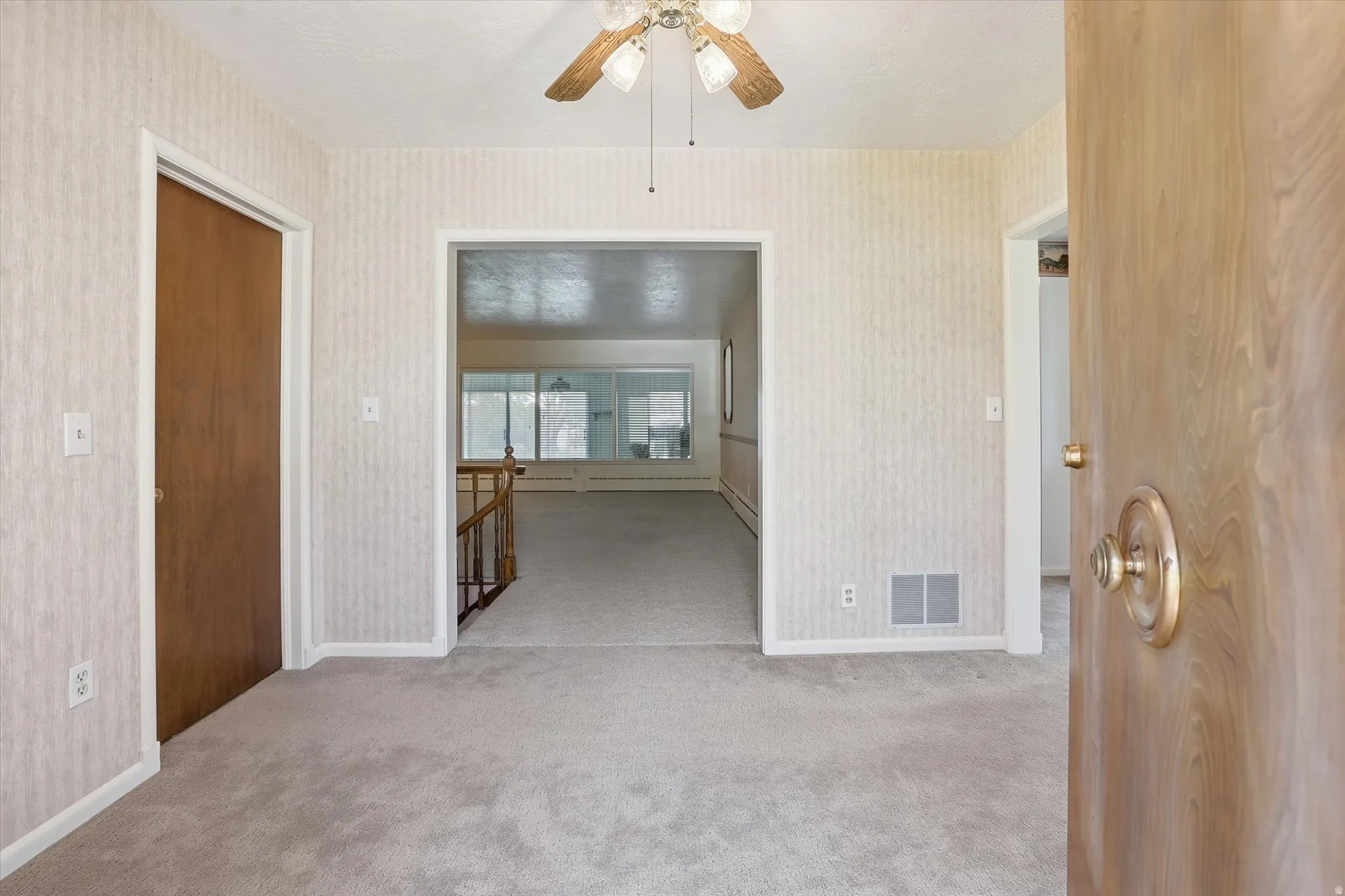 Carpeted room with a wooden ceiling fan and light fixture