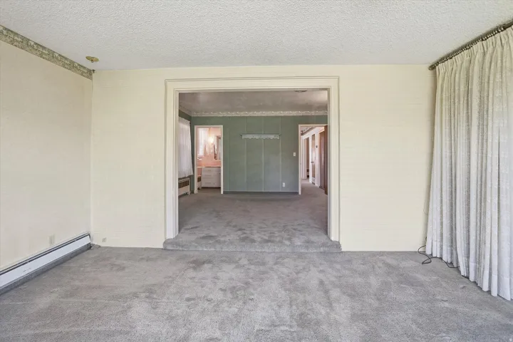 Carpeted interior space with a broad doorway opening into an additional room