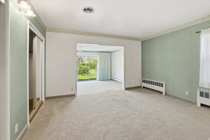 Carpeted room with light green walls, a white ceiling, and a wall-mounted light fixture
