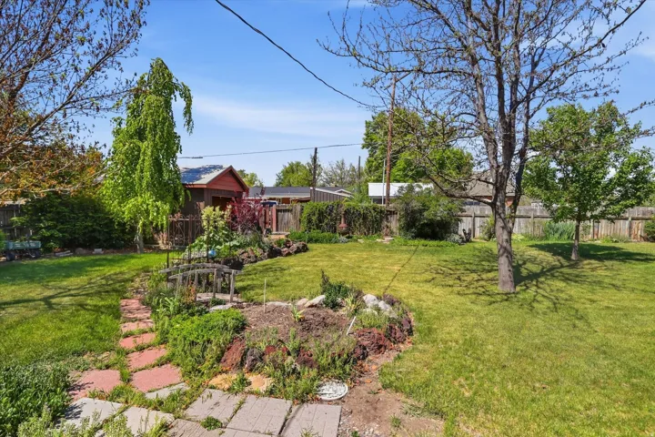Expansive yard featuring a manicured lawn, established trees, and mature landscaping