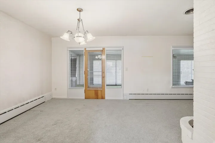 Carpeted interior space featuring white walls and a central chandelier