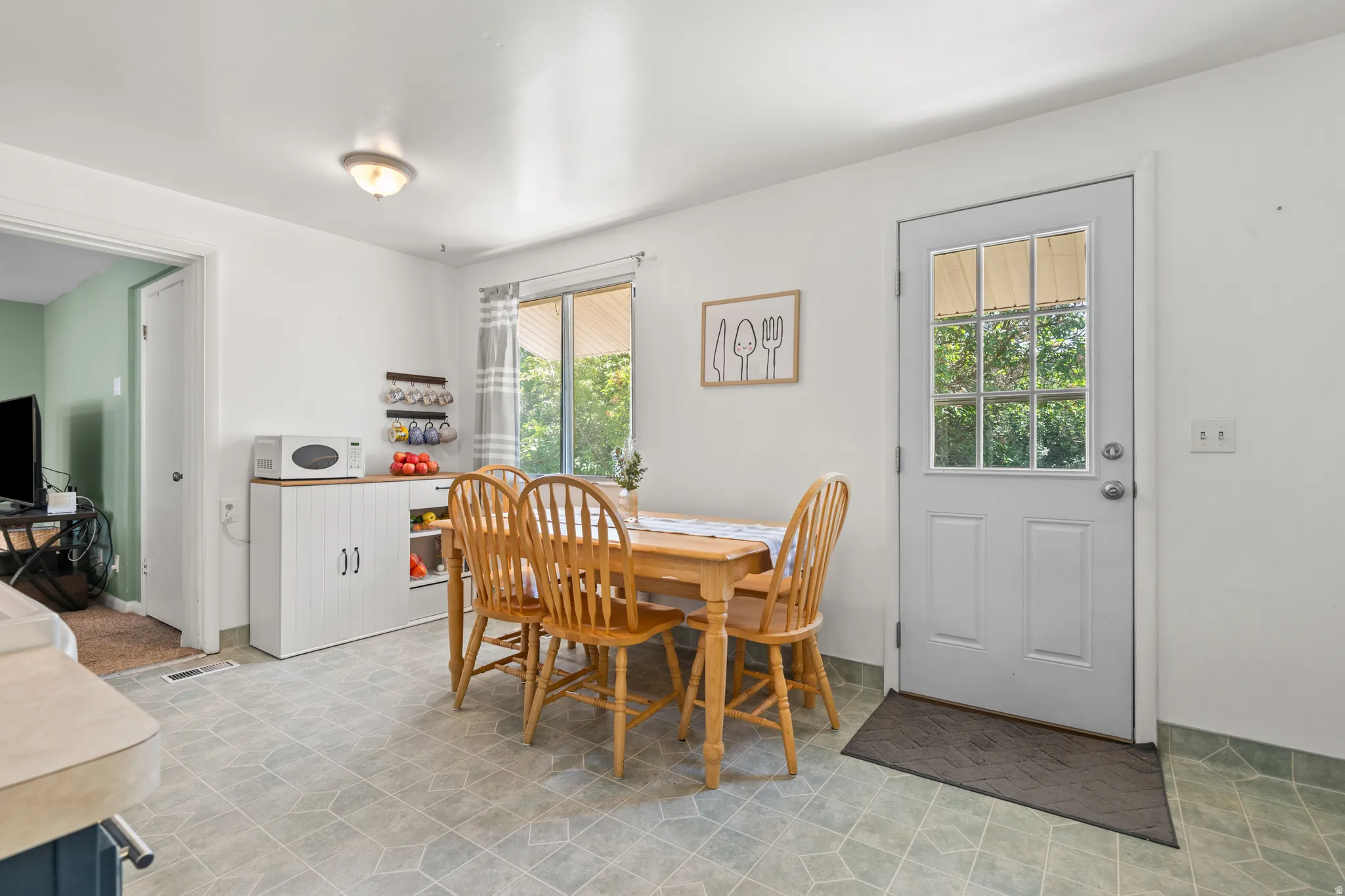 Kitchen-adjacent dining area featuring tiled flooring, a rear door with integrated window panes, and a window with natural light