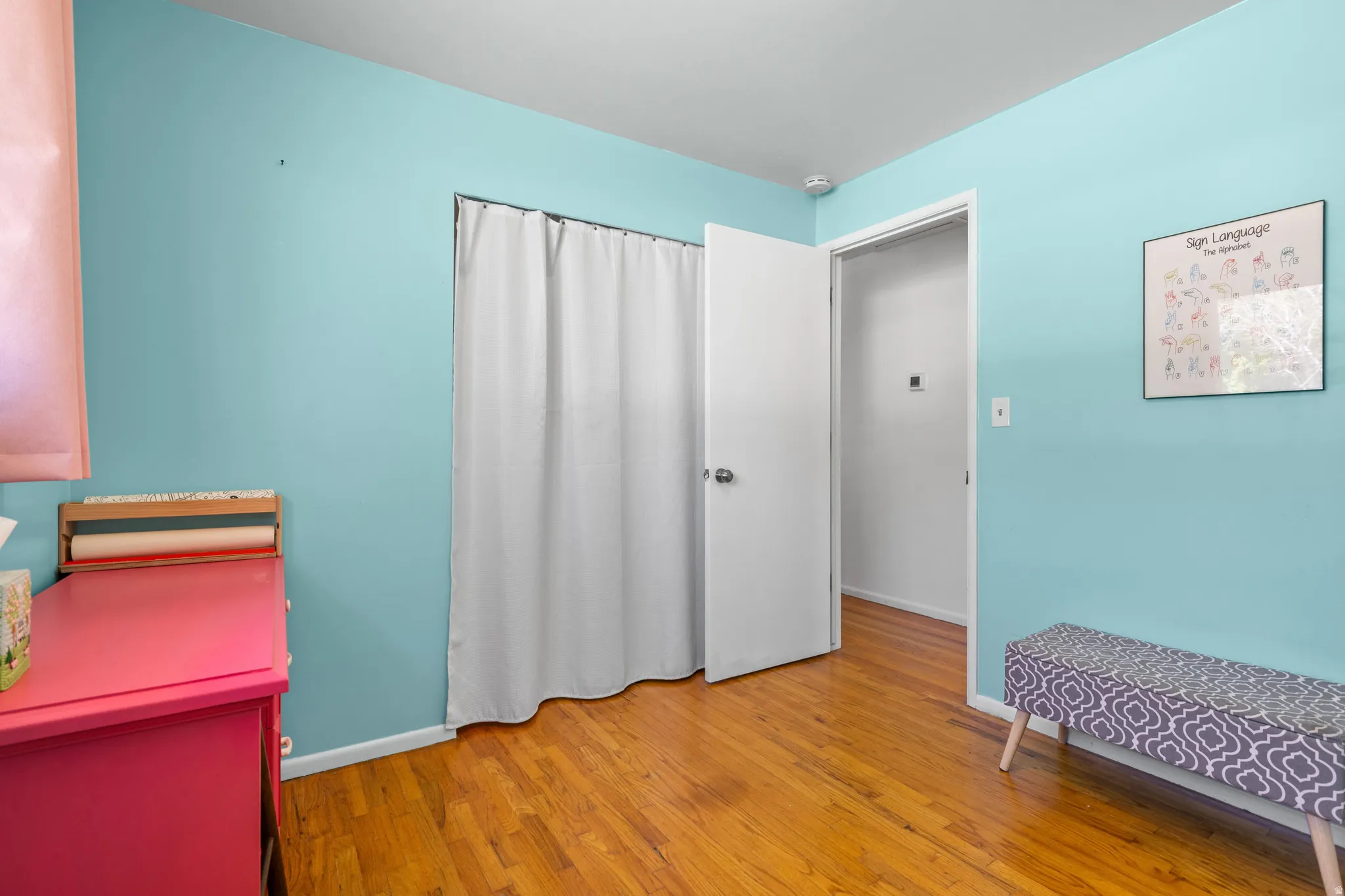 Hardwood-finish flooring with light blue wall paint, white trim, and a white interior door