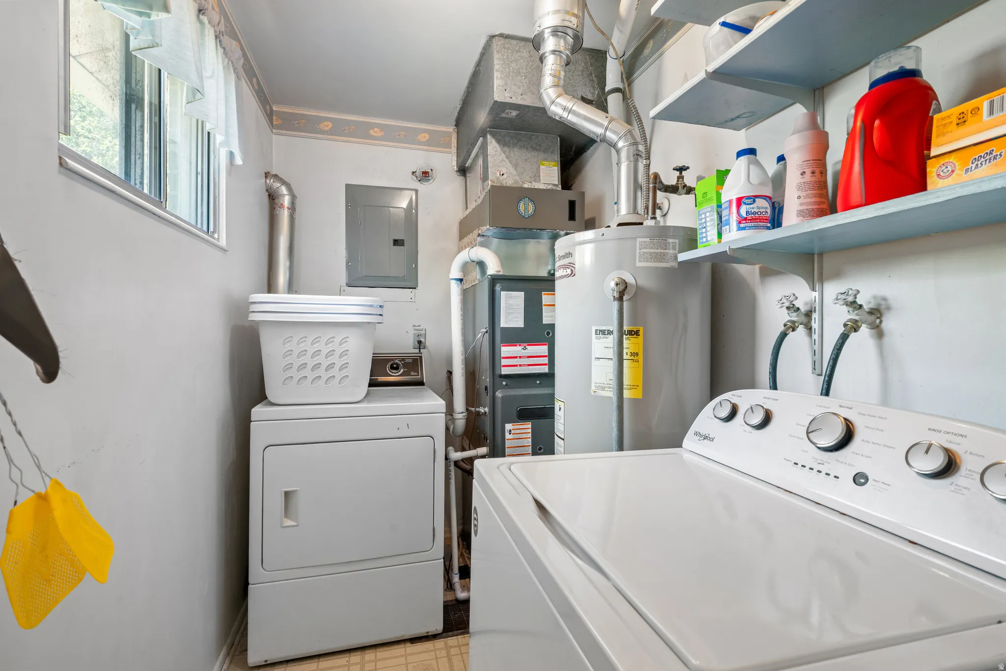 Dedicated utility room featuring a window, built-in shelving, water heater, and electrical panel