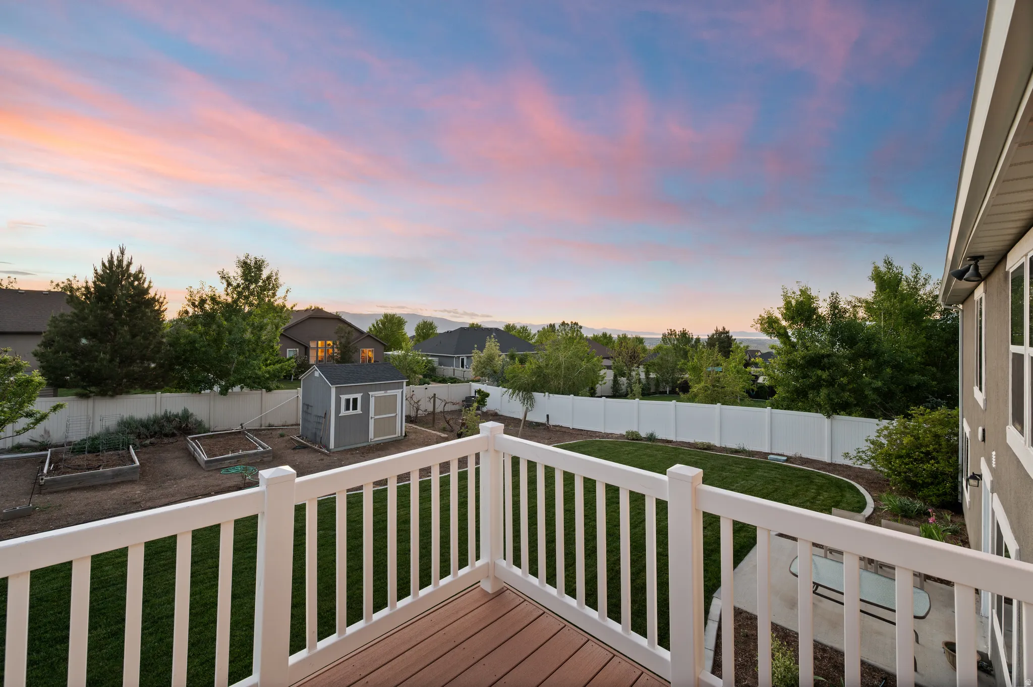 Composite decking with white railing overlooking a fenced backyard