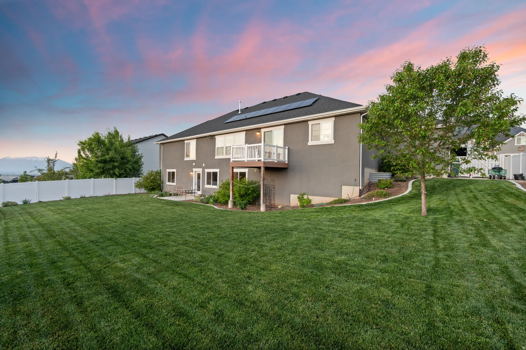 Expansive rear lawn with established tree and white vinyl fencing