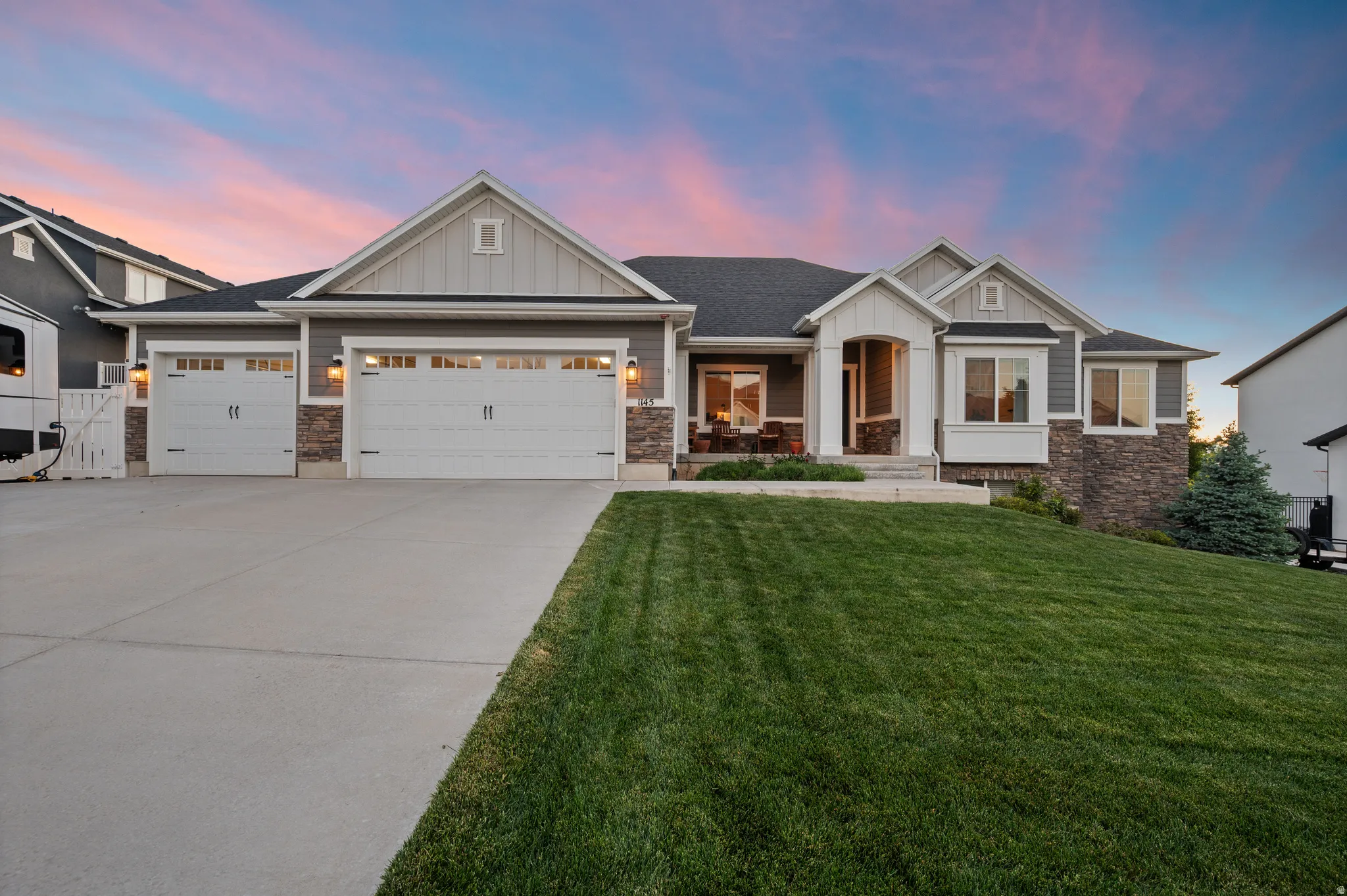 Contemporary rambler exterior featuring a stone and siding facade, a three-car garage, a covered front porch, and a bay window