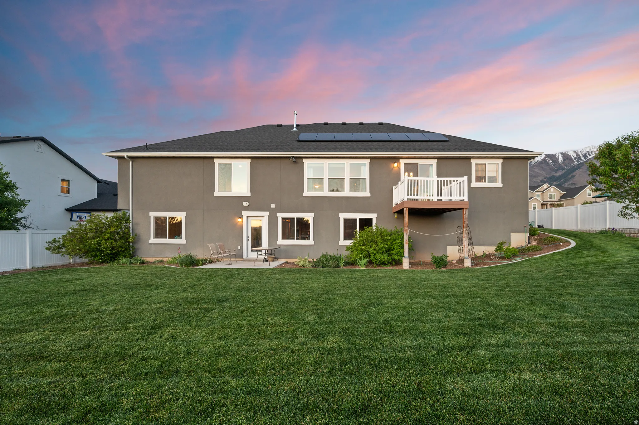 Expansive backyard featuring a manicured lawn, a concrete patio, and a second-story balcony