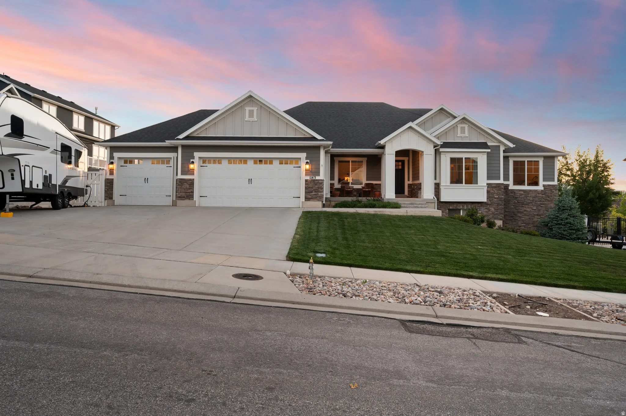 Contemporary ranch-style residence featuring a gray exterior with stone accents and white trim