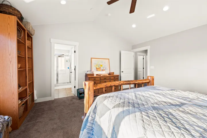 Master bedroom featuring an open doorway to a bathroom with tile flooring and a shower stall