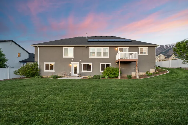Expansive backyard featuring a manicured lawn, a concrete patio, and a second-story balcony