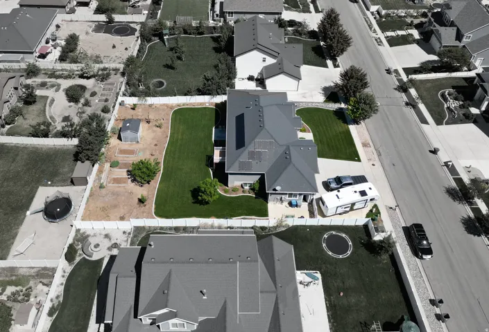 Expansive rear yard featuring a manicured lawn, established landscaping, and a dedicated garden area