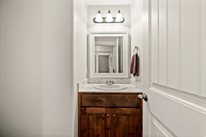 1/2 Bathroom vanity with a wood cabinet, undermount sink, and stone countertop