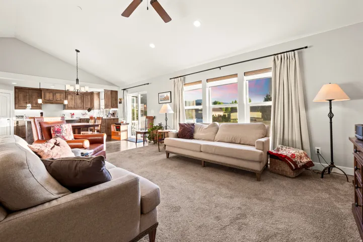 Spacious living area featuring vaulted ceilings, recessed lighting, and large windows with roller shades