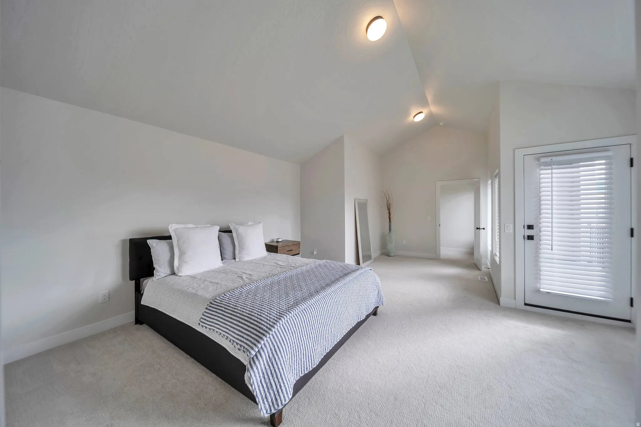 Vaulted ceiling room with recessed lighting and light-toned carpeting