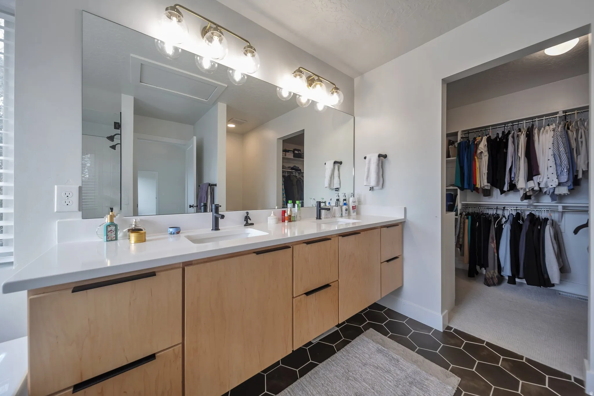 Dual vanity with undermount sinks, light wood-finish cabinetry, and matte black fixtures