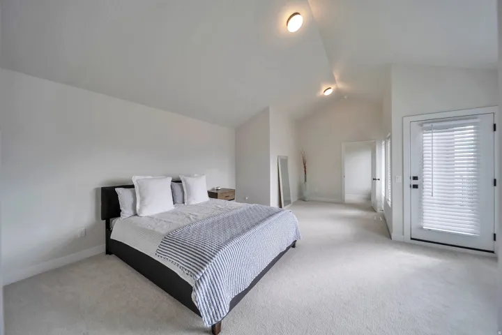 Vaulted ceiling room with recessed lighting and light-toned carpeting