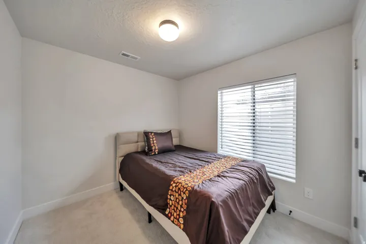 Bedroom featuring neutral wall paint, carpeted flooring, a window with horizontal blinds, a white door frame, and a flush-mount ceiling light