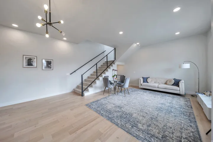 Spacious living area featuring light wood-finish flooring, recessed lighting, and a modern chandelier