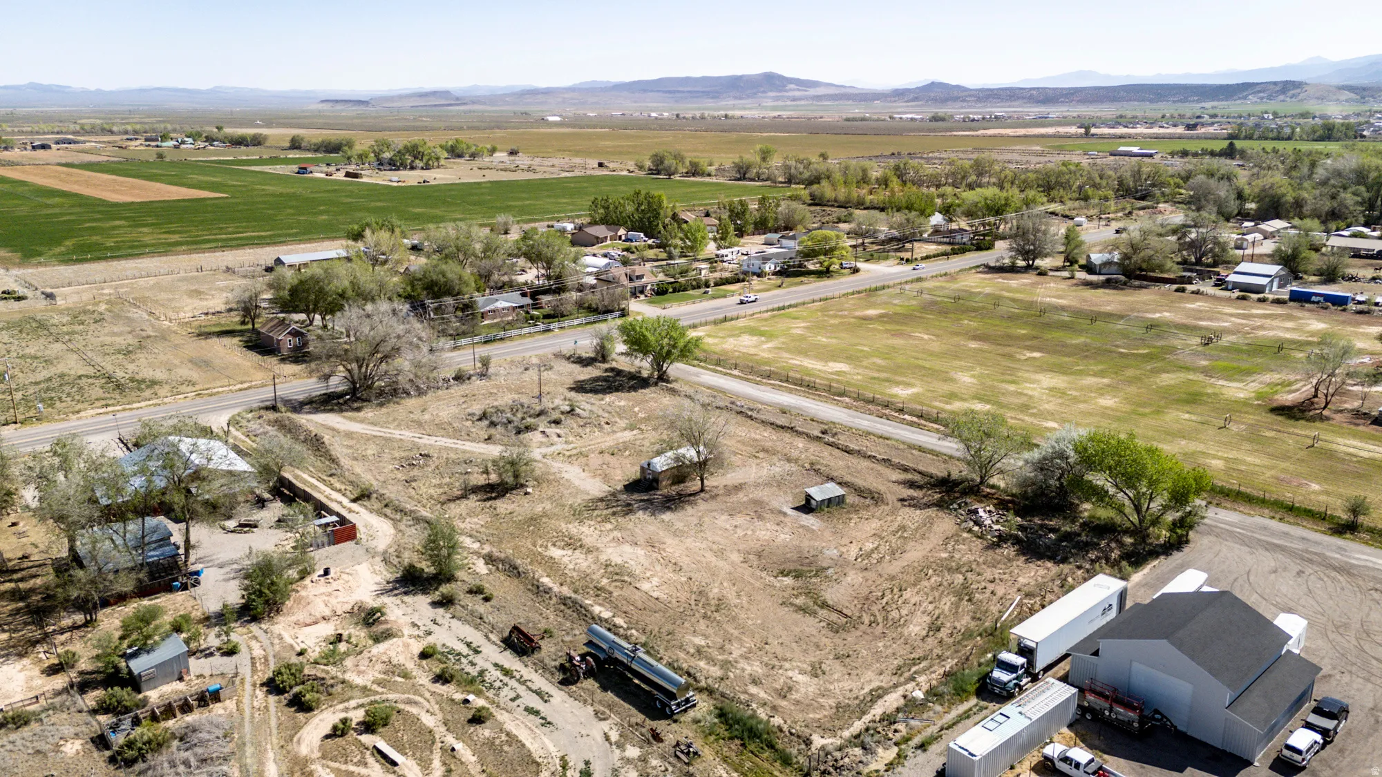 Expansive rural landscape featuring a mix of open fields, distant mountains, and scattered residential properties