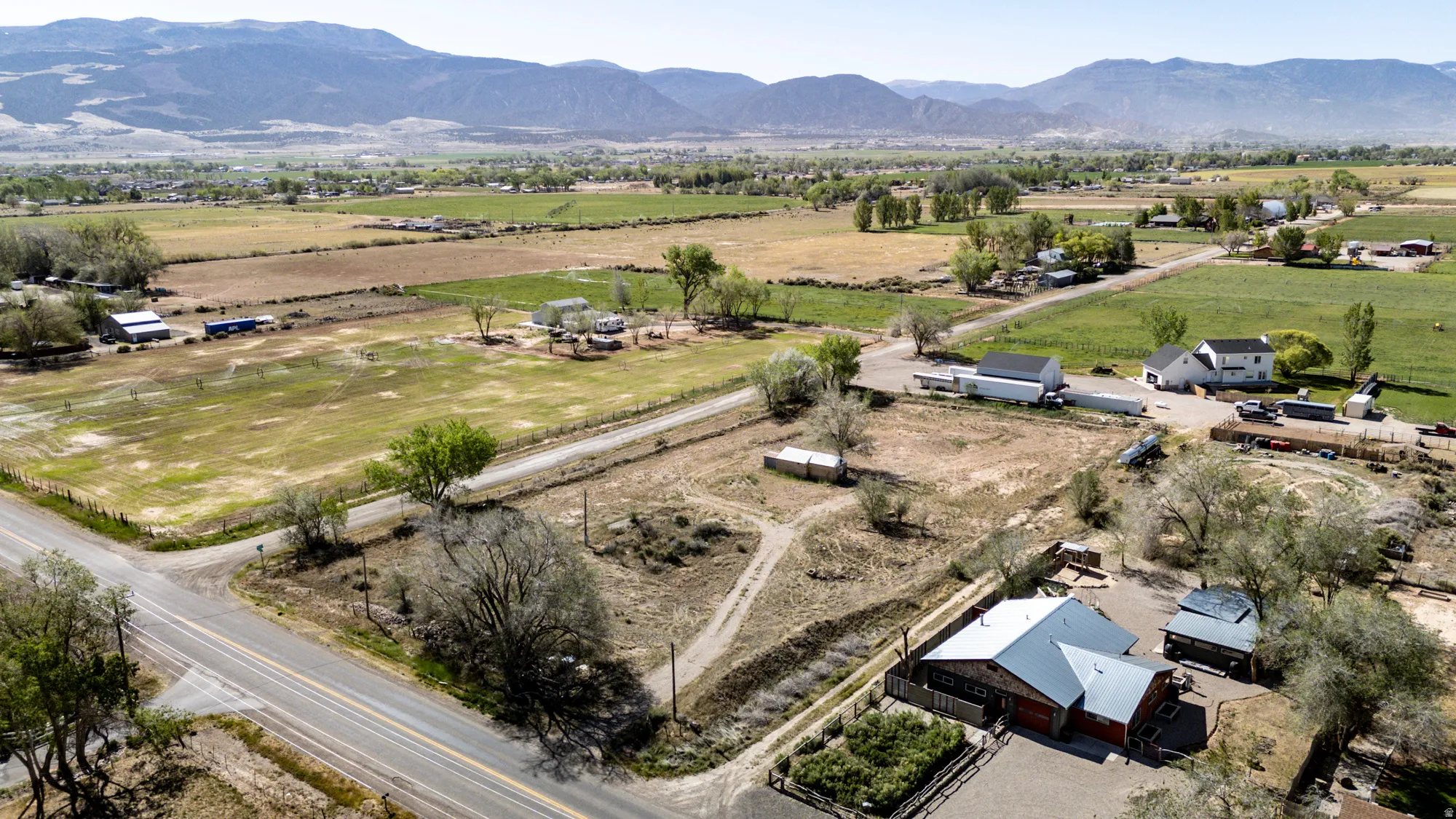 Expansive rural property featuring multiple structures, road frontage, and a mountainous backdrop