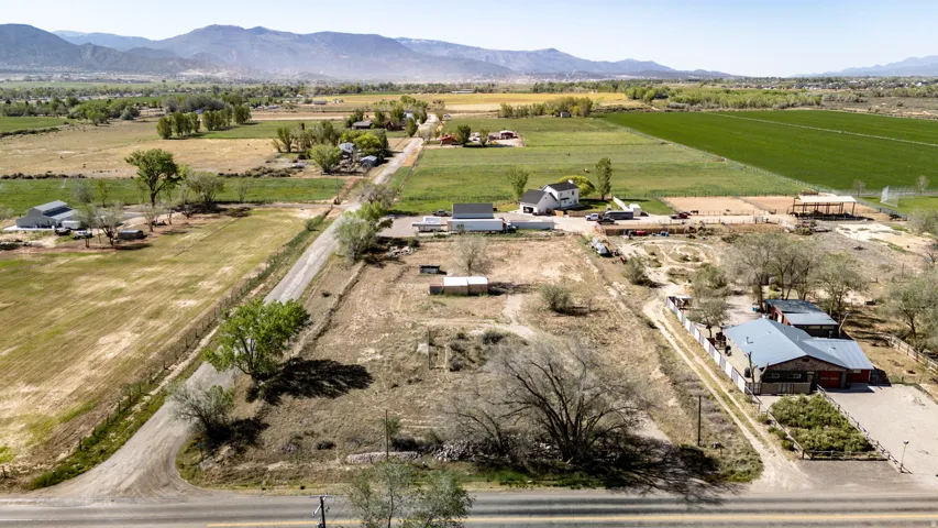 Expansive rural property featuring an established structure with a metal roof and red siding, multiple outbuildings, and extensive undeveloped land