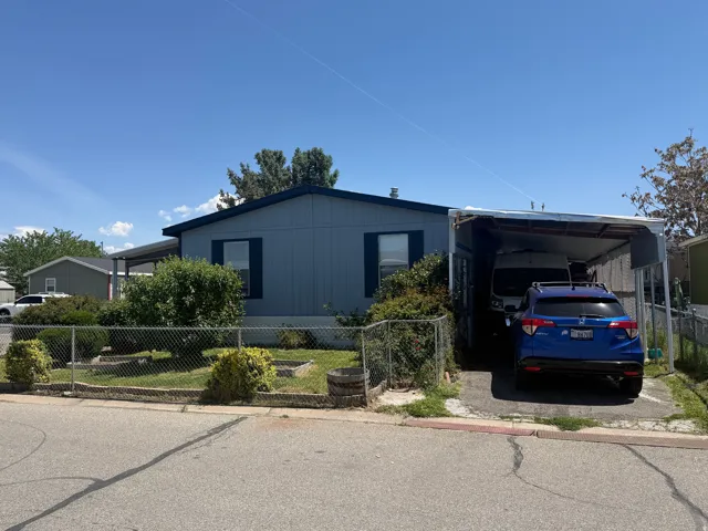 Single-story residence featuring a carport, chain-link fencing, and mature landscaping