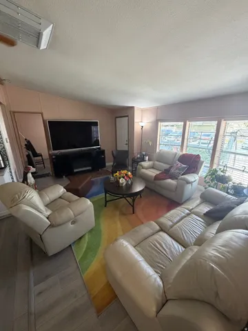 Living area featuring wood-finish flooring, a vaulted ceiling, and multiple windows