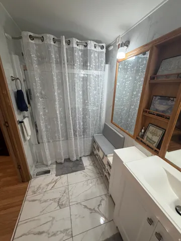 Bathroom featuring large-format marble-look floor tiles and a white vanity with an integrated sink