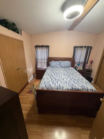 Bedroom featuring wood-finish flooring, a built-in closet with bifold doors, and a ceiling fan with integrated lighting