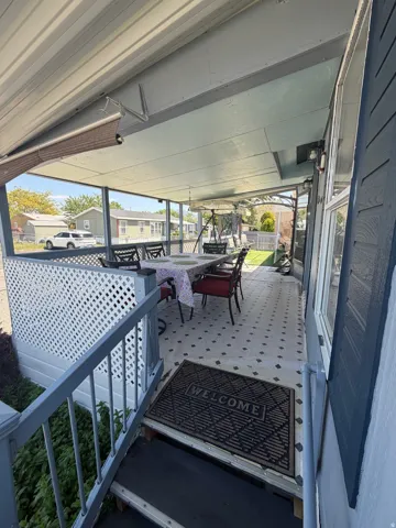 Covered exterior porch featuring patterned flooring and white lattice privacy screening