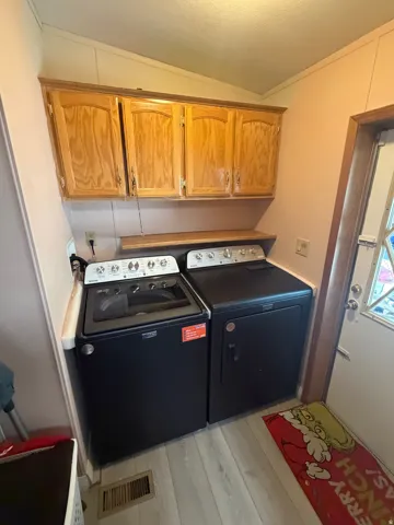 Dedicated laundry area featuring overhead wood cabinetry and a built-in shelf