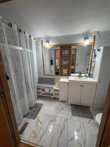 Bathroom featuring a vanity with an integrated sink, white cabinetry, a large wall-mounted mirror with a wood frame, and wall-mounted lighting