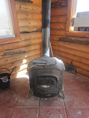 Cast iron wood-burning stove with a decorative facade, positioned on red tile flooring