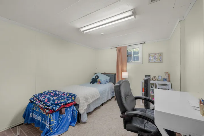 Carpeted room featuring light-colored paneling and a window providing natural light