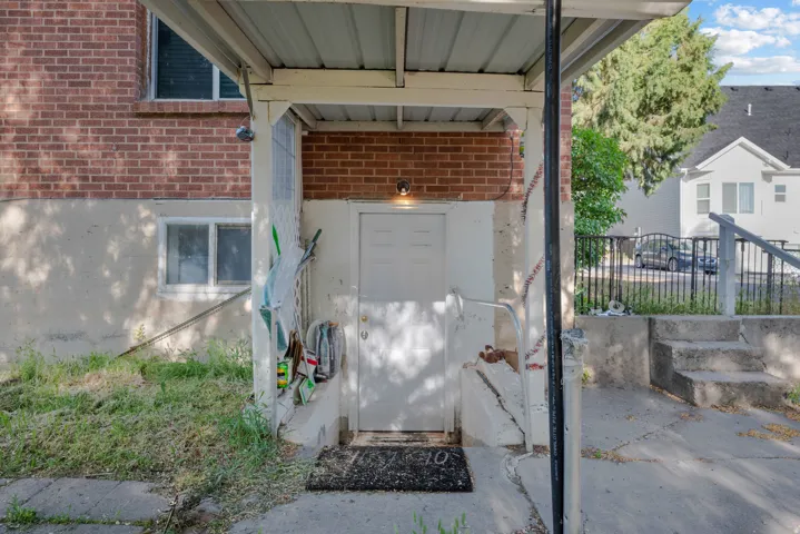 Covered outdoor entryway featuring a white exterior door, a brick wall accent, and concrete steps