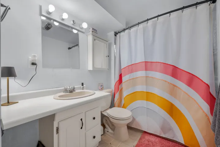 Bathroom featuring a vanity with an integrated sink, under-cabinet storage, an overhead vanity light fixture, a wall mirror, and a built-in wall cabinet