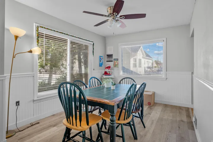 Dining area featuring wood-finish flooring, white beadboard wainscoting, and large windows with blinds