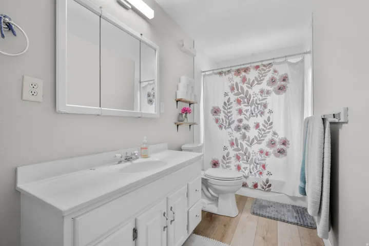 Bathroom featuring a white vanity with integrated sink, chrome faucet, and a large medicine cabinet with mirrored doors