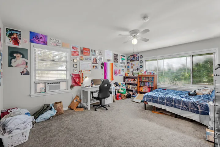 Carpeted interior room featuring light gray walls, white trim, and a white ceiling fan with integrated lighting