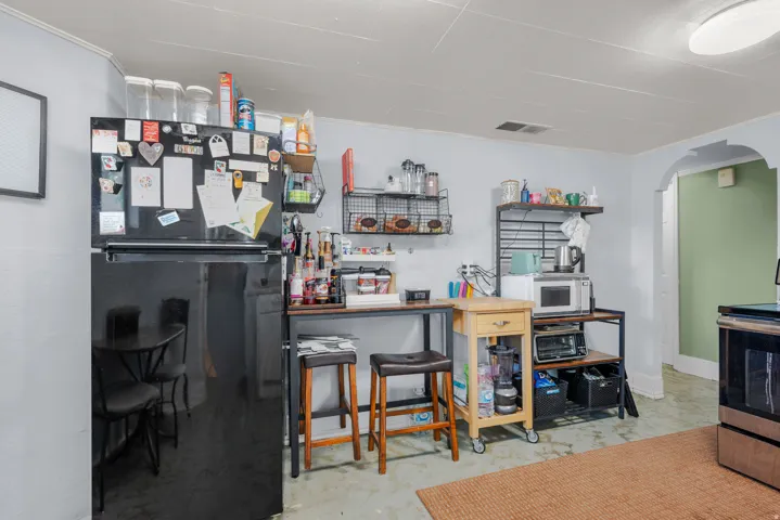Kitchen area featuring a black refrigerator, light blue painted walls, and a visible arched doorway