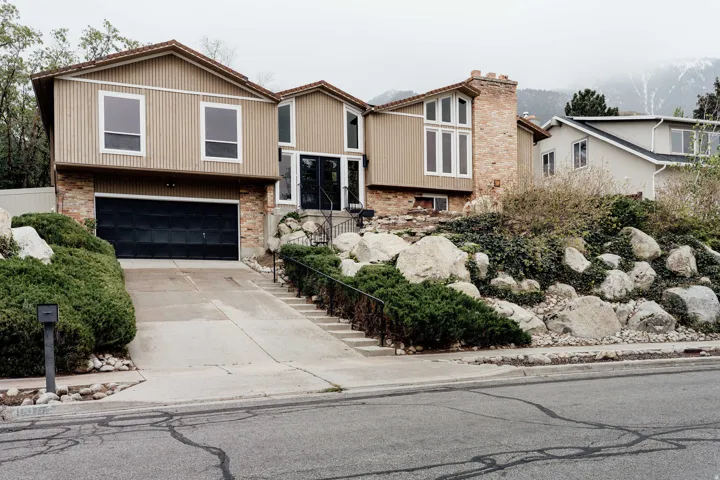 Split-level residence featuring a brick foundation and tan siding