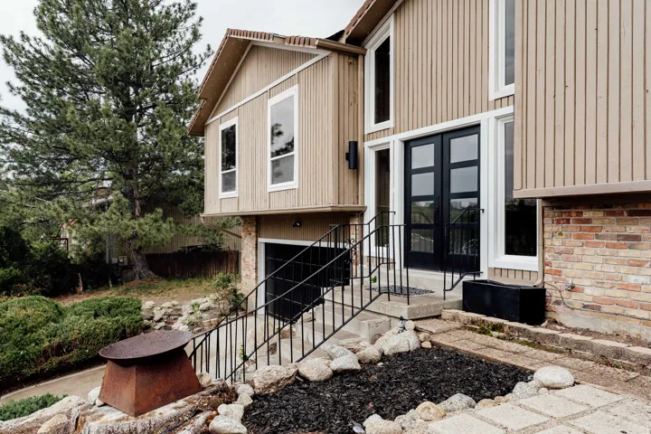 Modern architectural facade with vertical wood siding and a prominent black double-door entry